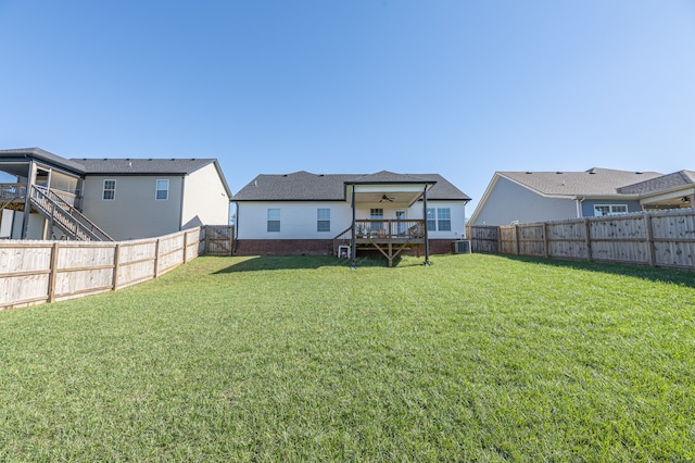 back of property with a lawn, ceiling fan, cooling unit, and a deck