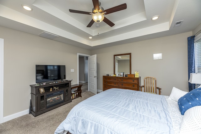 carpeted bedroom with ceiling fan and a tray ceiling