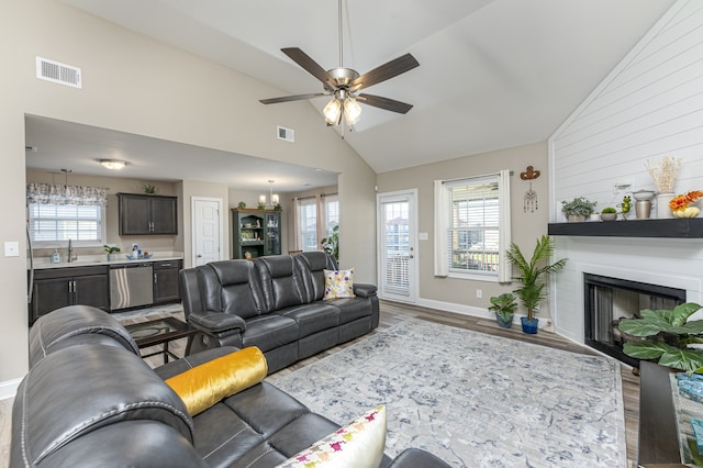 living room with hardwood / wood-style floors, ceiling fan with notable chandelier, high vaulted ceiling, and a wealth of natural light