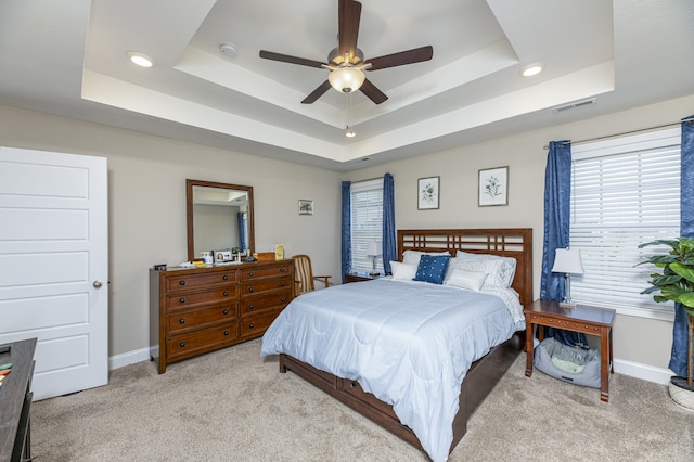 carpeted bedroom with ceiling fan and a tray ceiling