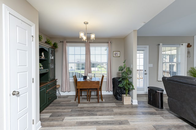 dining space featuring light hardwood / wood-style floors, a wealth of natural light, and a notable chandelier