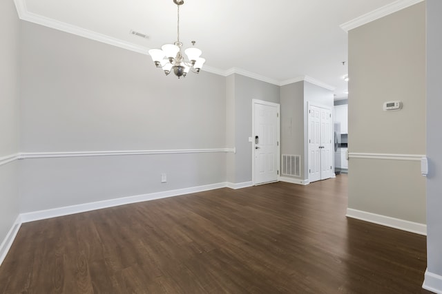 spare room featuring crown molding, dark wood-type flooring, and a notable chandelier