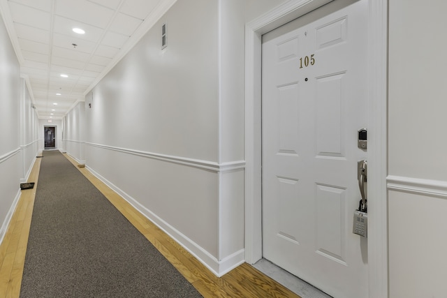 hall with wood-type flooring and a paneled ceiling