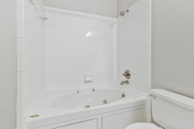 bathroom with tiled shower / bath combo and toilet