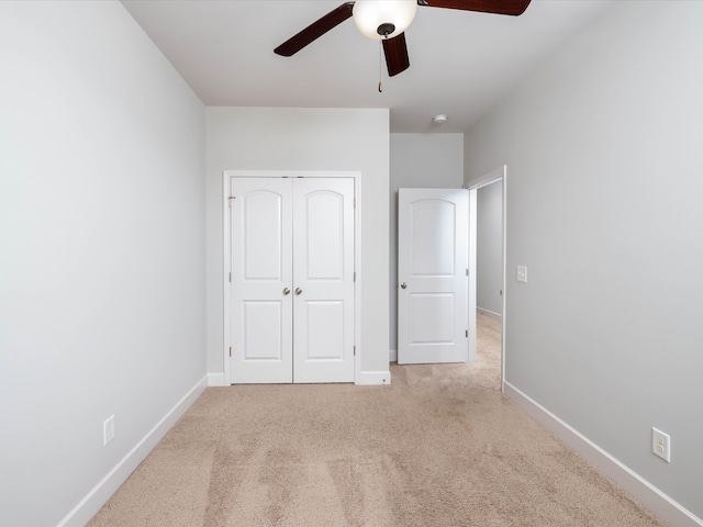 unfurnished bedroom with ceiling fan, light carpet, and a closet