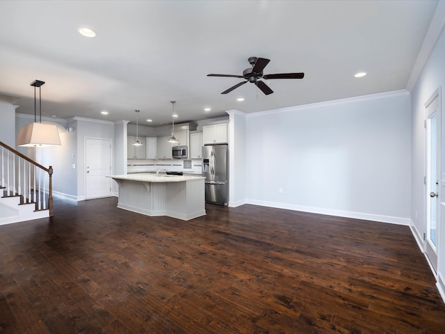 kitchen featuring pendant lighting, a kitchen breakfast bar, a center island with sink, and stainless steel appliances