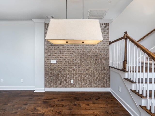 stairs with hardwood / wood-style floors, ornamental molding, and brick wall