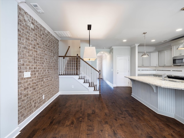 kitchen with pendant lighting, a kitchen bar, sink, dark hardwood / wood-style flooring, and light stone counters