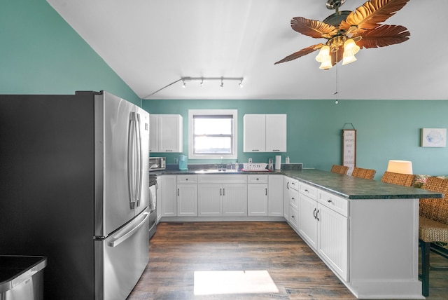 kitchen featuring white cabinets, a breakfast bar area, dark hardwood / wood-style floors, kitchen peninsula, and stainless steel appliances