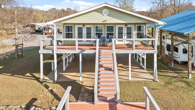 rear view of property with french doors, ceiling fan, a wooden deck, and a lawn