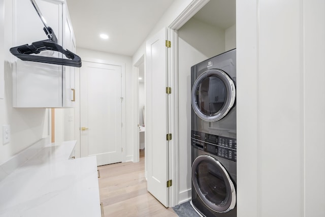 washroom featuring stacked washer and dryer and light hardwood / wood-style flooring