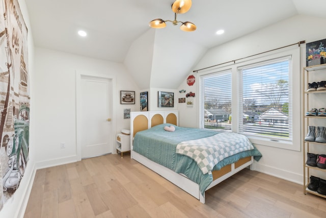 bedroom featuring a chandelier, light hardwood / wood-style floors, and lofted ceiling