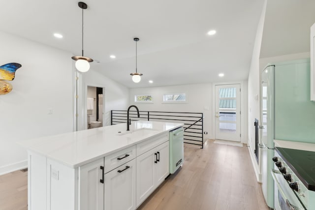 kitchen with stainless steel dishwasher, decorative light fixtures, a center island with sink, light hardwood / wood-style floors, and white cabinetry