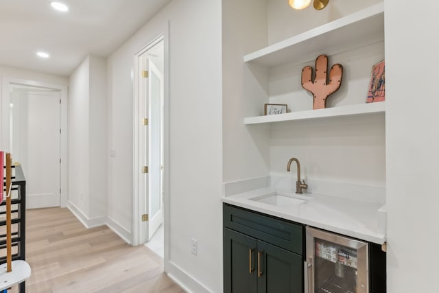 bar featuring sink, wine cooler, and light hardwood / wood-style flooring