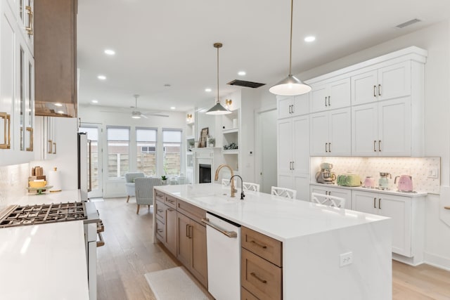 kitchen featuring white appliances, white cabinets, sink, light hardwood / wood-style flooring, and a large island