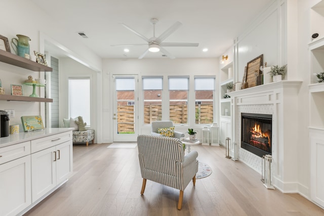 sitting room with ceiling fan, light hardwood / wood-style flooring, and built in features