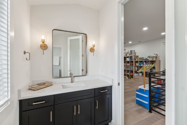 bathroom with vanity, wood-type flooring, and vaulted ceiling