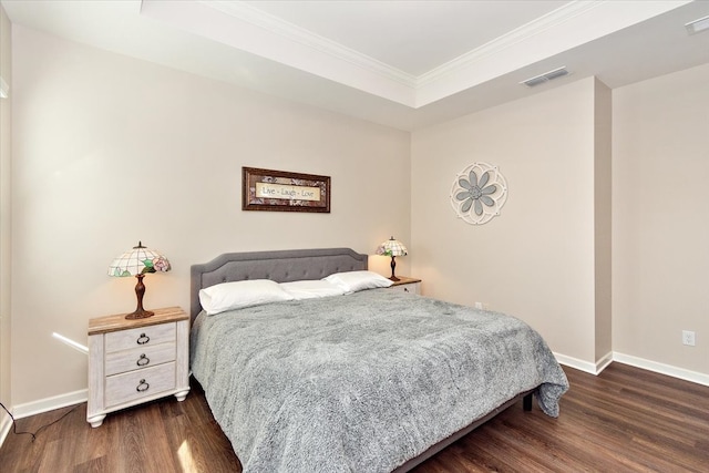 bedroom featuring dark hardwood / wood-style flooring, a raised ceiling, and ornamental molding