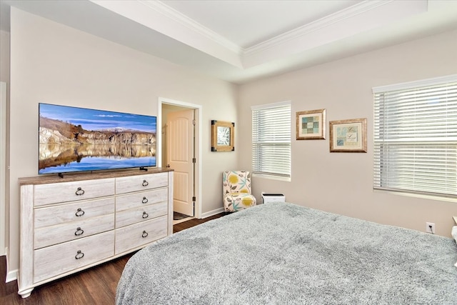 bedroom with dark hardwood / wood-style floors, a tray ceiling, and crown molding