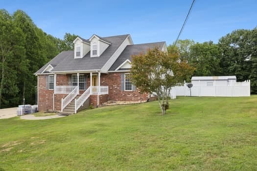 cape cod-style house featuring covered porch and a front lawn