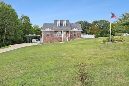 cape cod house with a front lawn and a carport