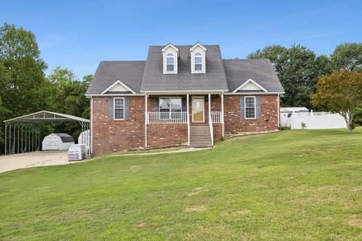 cape cod home featuring a carport, covered porch, and a front yard