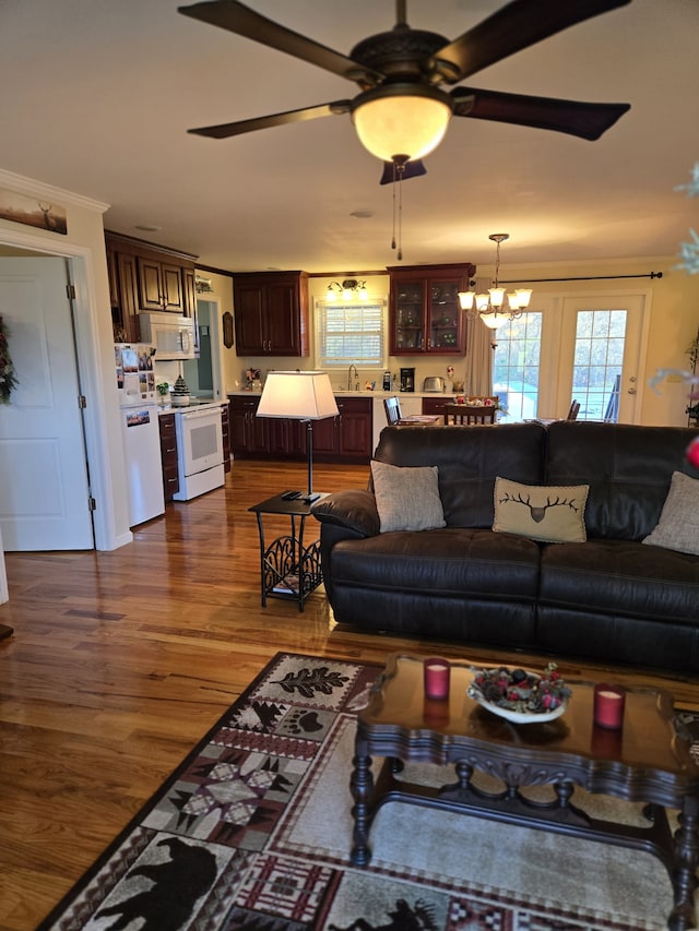 living room with ceiling fan with notable chandelier, dark hardwood / wood-style floors, crown molding, and sink