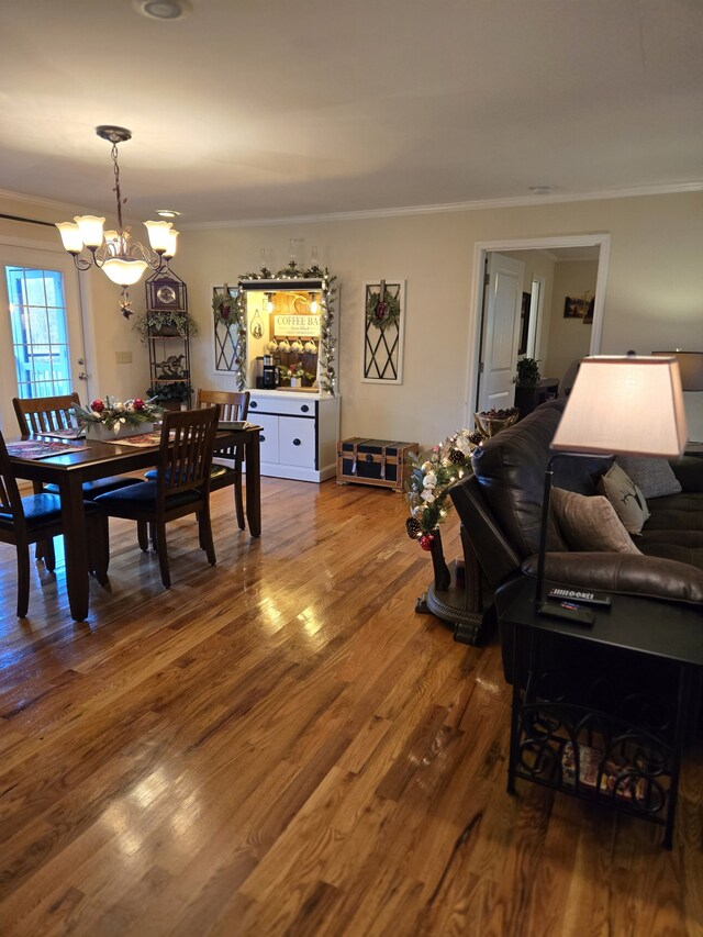 dining area with crown molding, hardwood / wood-style floors, and a notable chandelier