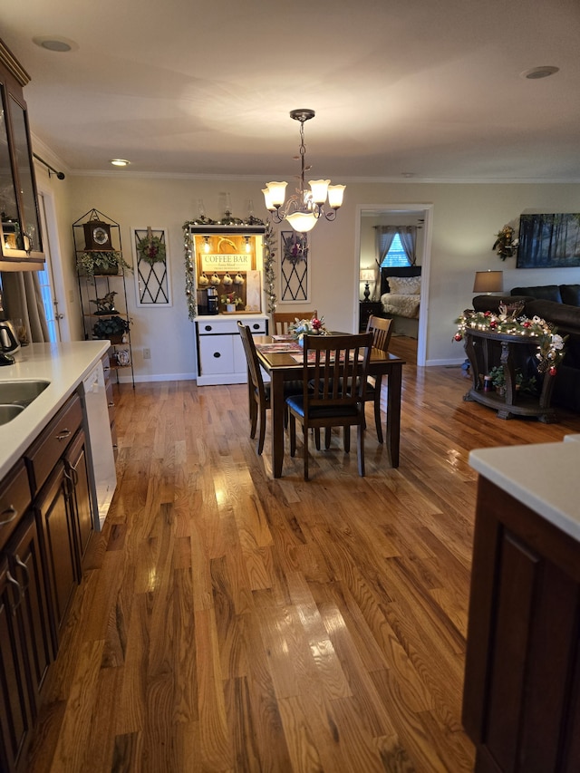 dining area featuring crown molding, light hardwood / wood-style flooring, sink, and a notable chandelier