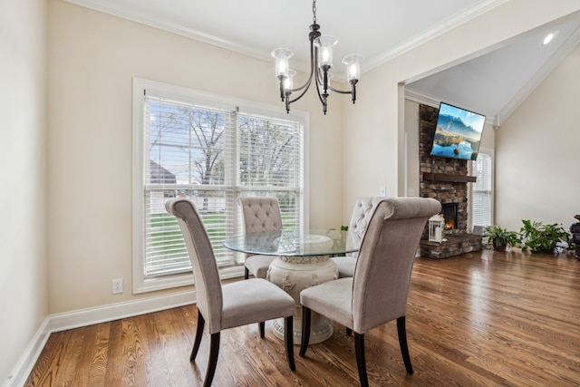 dining room featuring plenty of natural light, crown molding, wood-type flooring, and a fireplace