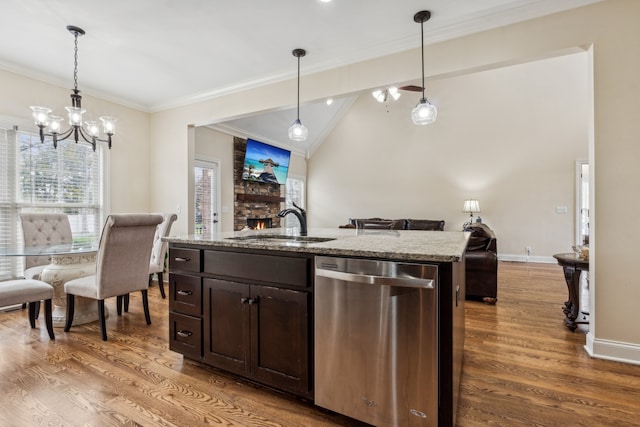 kitchen featuring a kitchen island with sink, light stone countertops, hardwood / wood-style floors, and stainless steel dishwasher