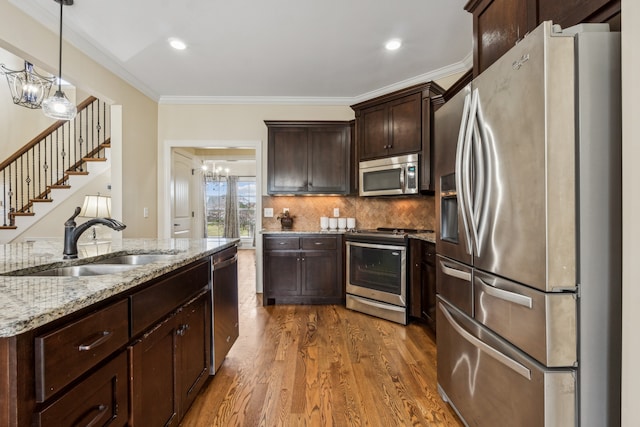 kitchen with dark brown cabinetry, sink, stainless steel appliances, crown molding, and hardwood / wood-style flooring