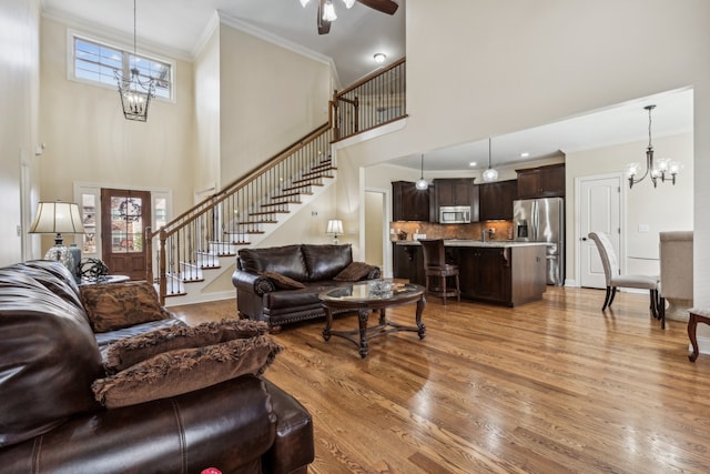 living room with a high ceiling, light hardwood / wood-style floors, plenty of natural light, and crown molding