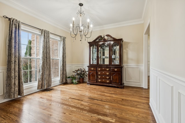 dining space featuring an inviting chandelier, ornamental molding, and hardwood / wood-style flooring