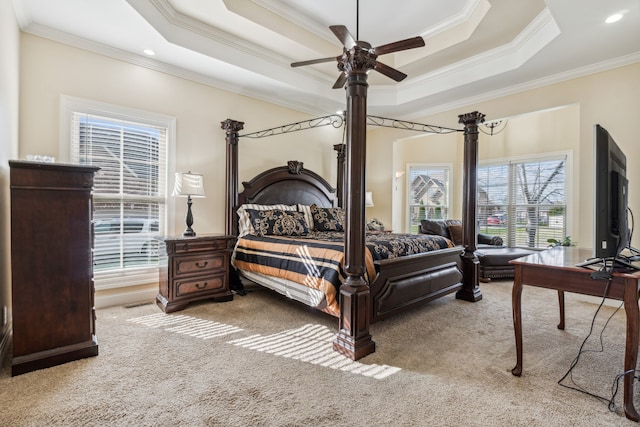 carpeted bedroom with ceiling fan, crown molding, and a tray ceiling