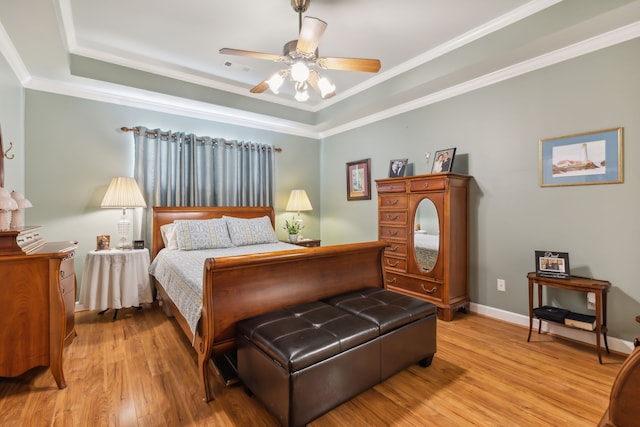 bedroom featuring a tray ceiling, ceiling fan, crown molding, and light hardwood / wood-style floors