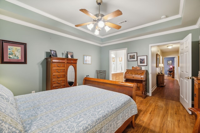 bedroom featuring ensuite bathroom, a raised ceiling, crown molding, ceiling fan, and wood-type flooring