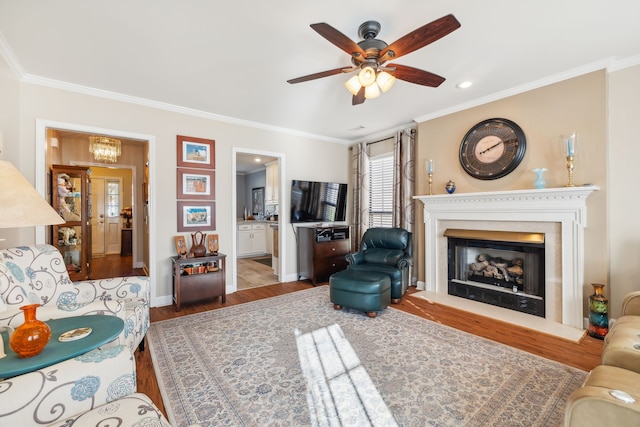 living room featuring ceiling fan with notable chandelier, crown molding, and dark wood-type flooring