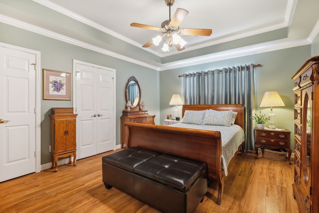 bedroom with hardwood / wood-style floors, a tray ceiling, ceiling fan, and ornamental molding