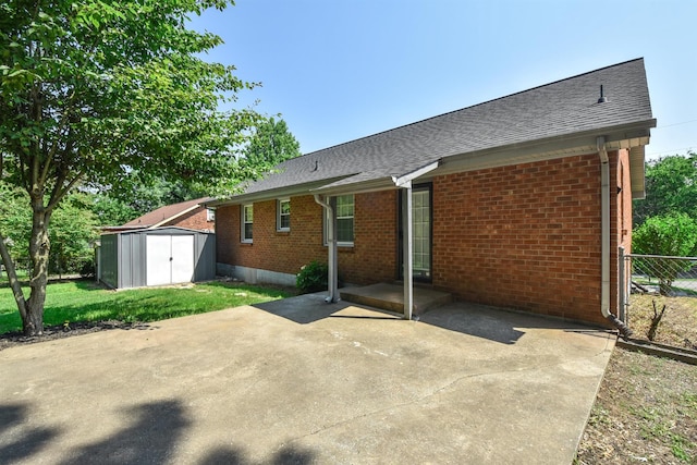 rear view of property featuring a shed and a patio