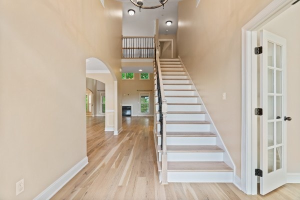 stairs with hardwood / wood-style floors, a high ceiling, and an inviting chandelier