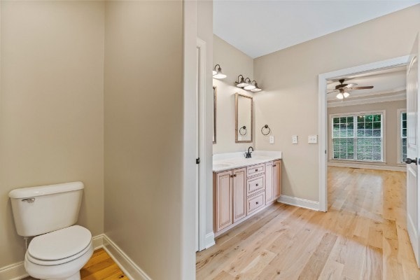 bathroom featuring ceiling fan, toilet, vanity, and hardwood / wood-style flooring