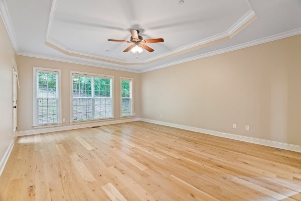 unfurnished room with a raised ceiling, ceiling fan, light hardwood / wood-style flooring, and ornamental molding