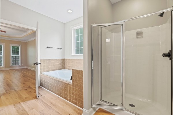 bathroom featuring separate shower and tub, crown molding, and wood-type flooring