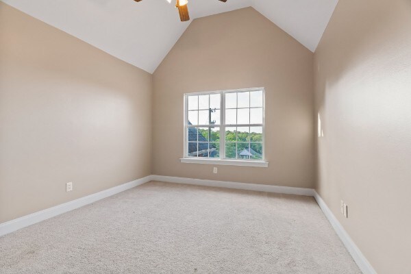 carpeted empty room featuring ceiling fan and high vaulted ceiling