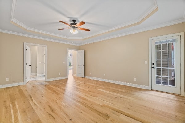 unfurnished room with a raised ceiling, light hardwood / wood-style flooring, and ornamental molding