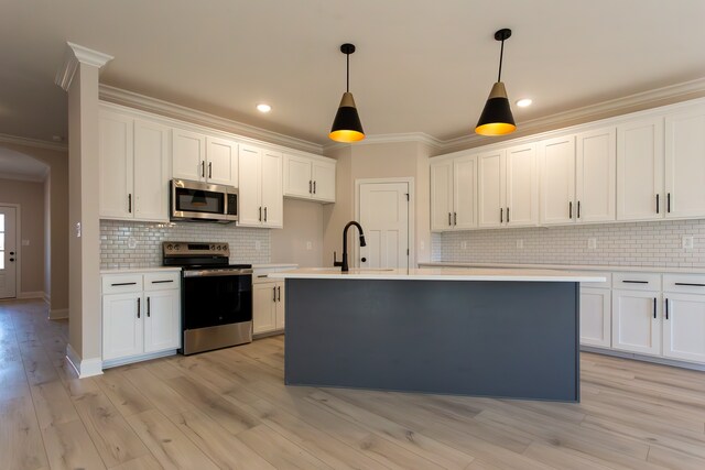 kitchen featuring ornamental molding, appliances with stainless steel finishes, decorative light fixtures, and white cabinets