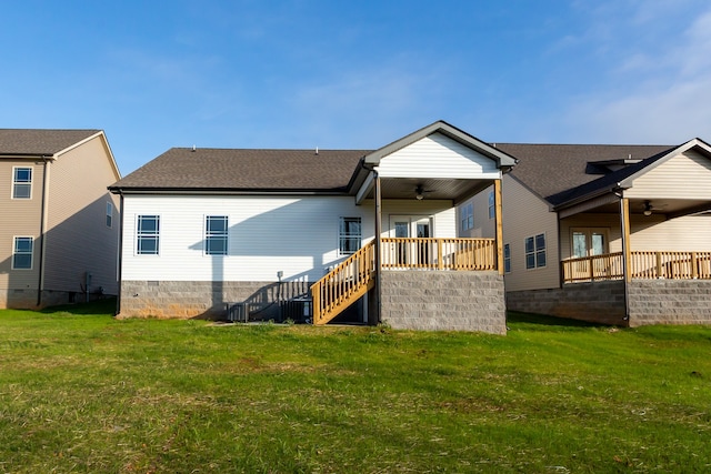 rear view of house featuring ceiling fan and a yard