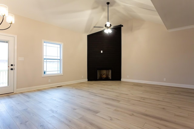 unfurnished living room with a healthy amount of sunlight, vaulted ceiling, a large fireplace, and light hardwood / wood-style flooring