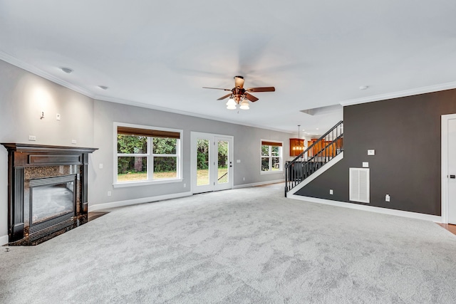 unfurnished living room featuring crown molding, a high end fireplace, light carpet, and ceiling fan